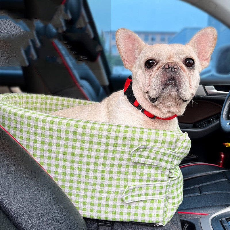 グリーンのチェック柄車用ペットベッドに座る小型犬